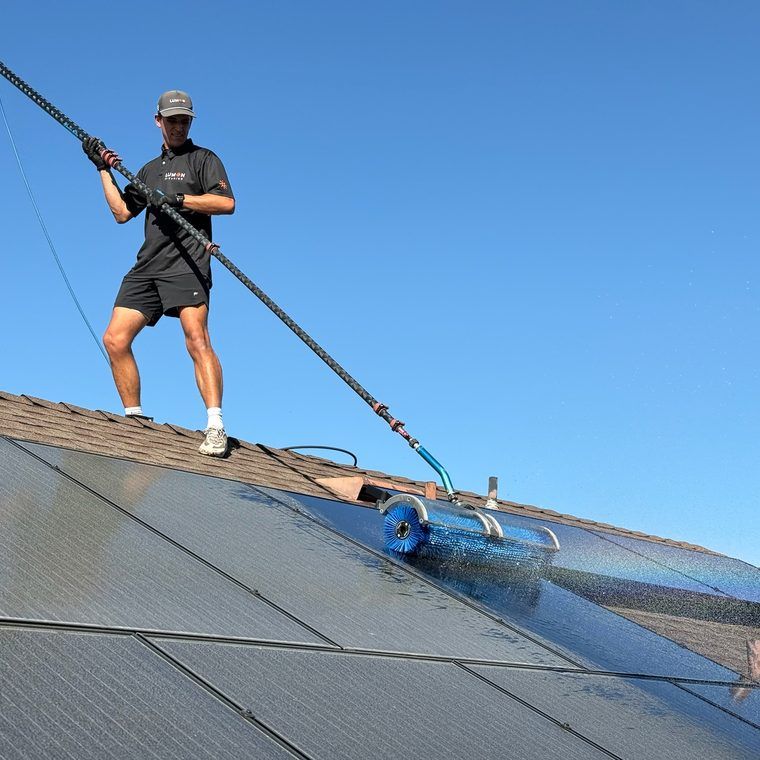 Lumon technician cleaning rooftop solar with a pole brush
