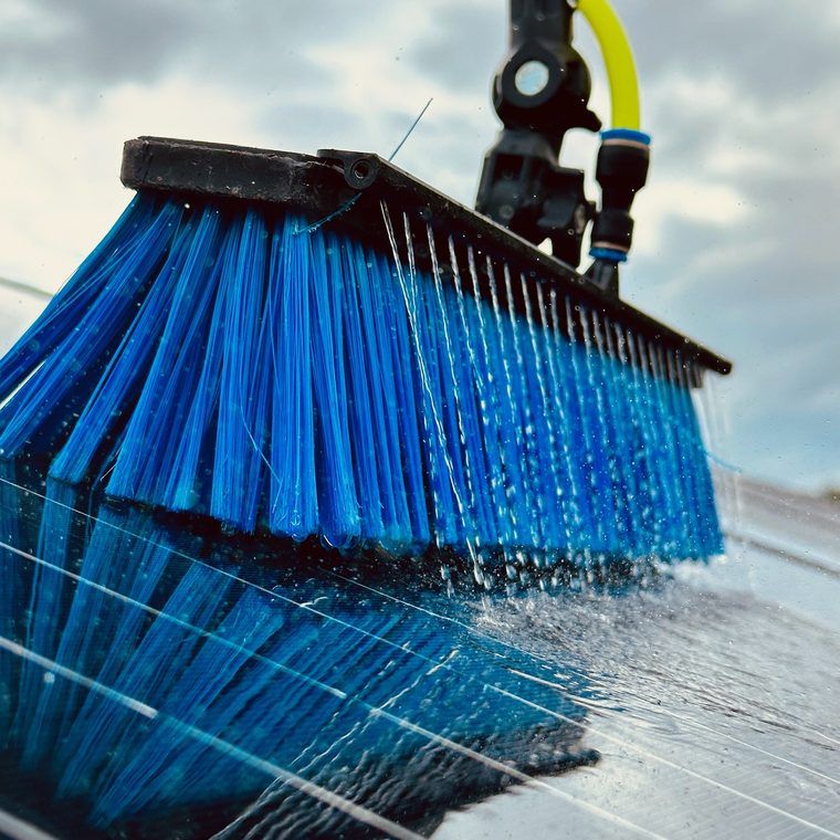 Water-fed brush rinsing a solar panel