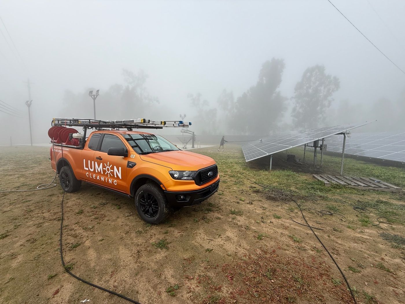 Lumon technician water fed cleaning a ground mounted solar array in the Central Valley
