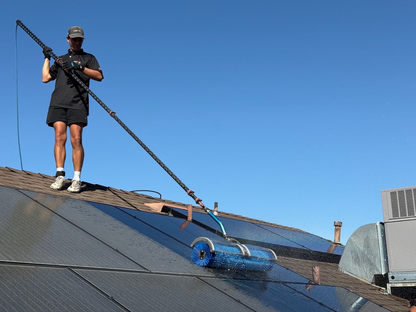 Technician brushing a rooftop solar panel clean